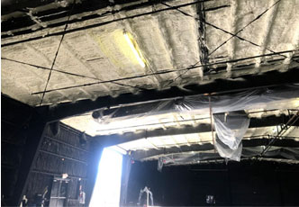 Interior view of a warehouse or industrial space with exposed ceiling insulation and partially covered pipework, expertly installed by a top-rated insulation contractor.