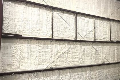 after-0518 A wall with exposed metal studs and horizontal beams is expertly covered in spray foam insulation by a professional insulation installer.