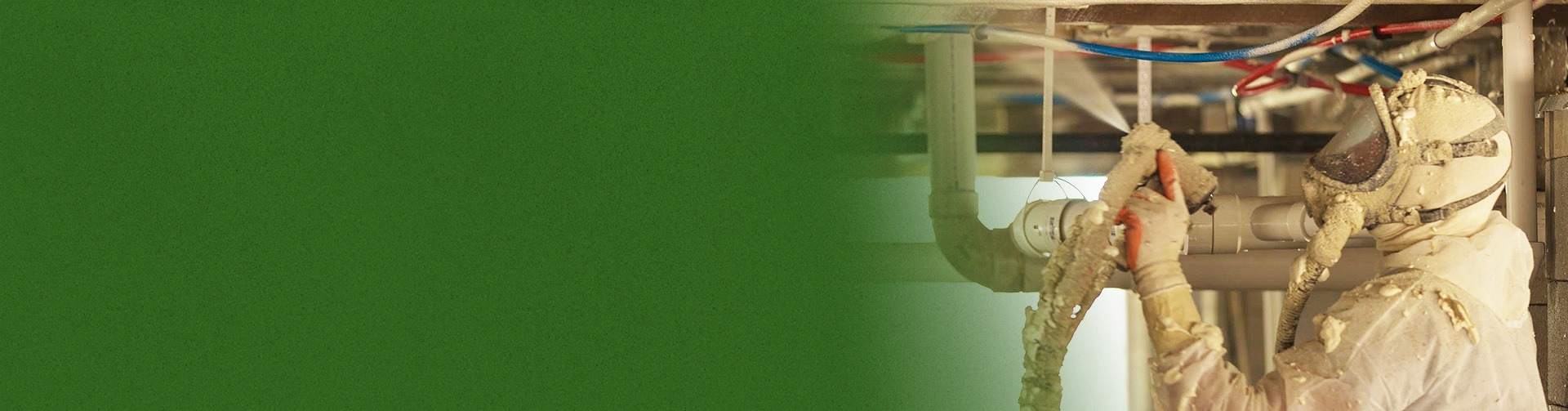 A worker in protective gear from an insulation company applies spray foam insulation to pipes. The left side of the image is obscured by a green area.